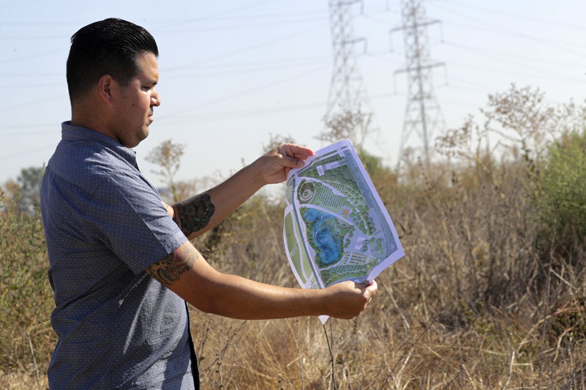 Landscape designer Matt Romero holds a rendering of a planned urban park and reconstructed wetland in South Gate.