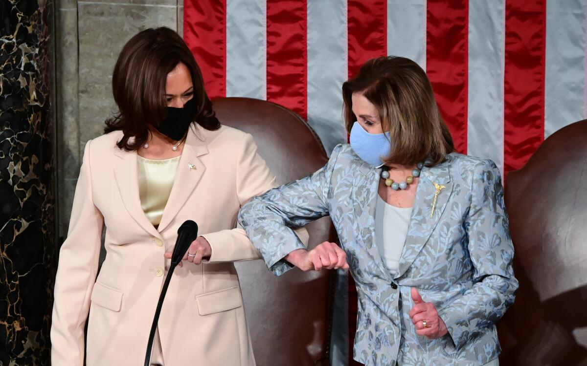 Kamala Harris and Nancy Pelosi touch elbows on the dais in the House chambers