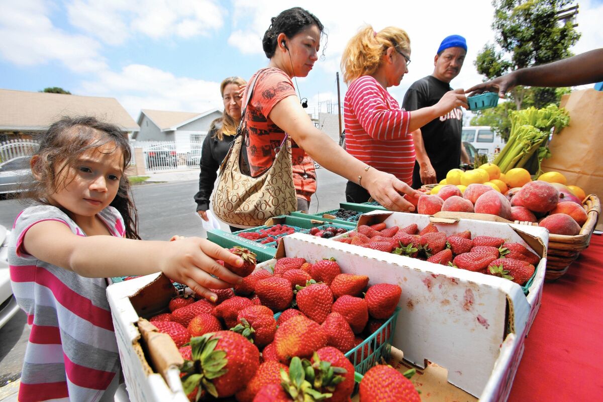 Belynda Umanzor, 3, left, and her mother Mily, 34, second from left, look at fruit at a produce stand in South Los Angeles.