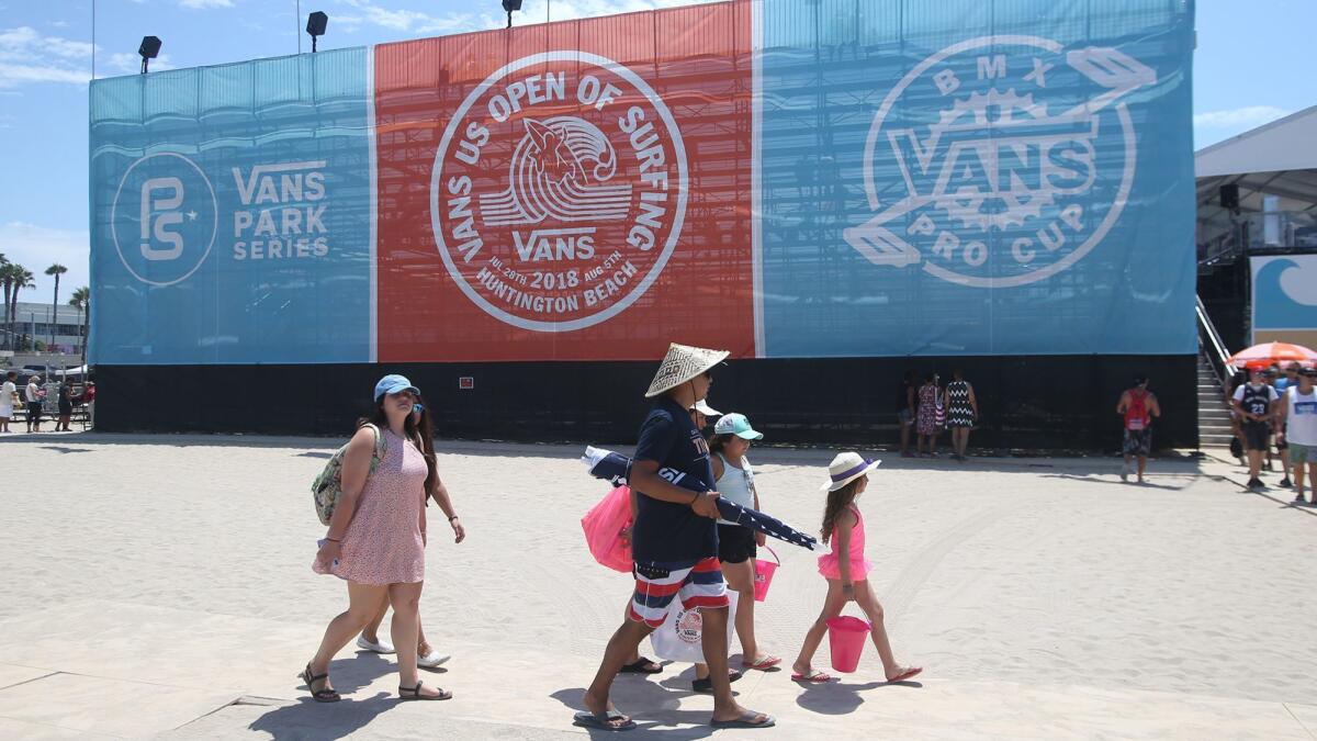 Visitors walk past a grandstand during the 2018 Vans U.S. Open of Surfing in Huntington Beach, which ended its nine-day run Sunday.