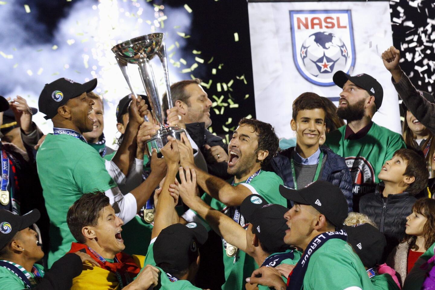 New York Cosmos player Raul Gonzalez (C) celebrates with teammate Marcos Senna (L) and other teammates following their team's win over the Ottawa Fury for the NASL Championship in Hempstead, New York, November 15, 2015. REUTERS/Brendan McDermid ** Usable by SD ONLY **