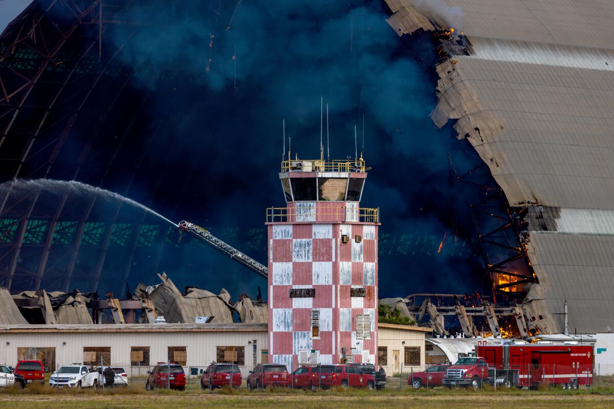 A stubborn fire burns inside a hangar at the former Tustin Air Base.