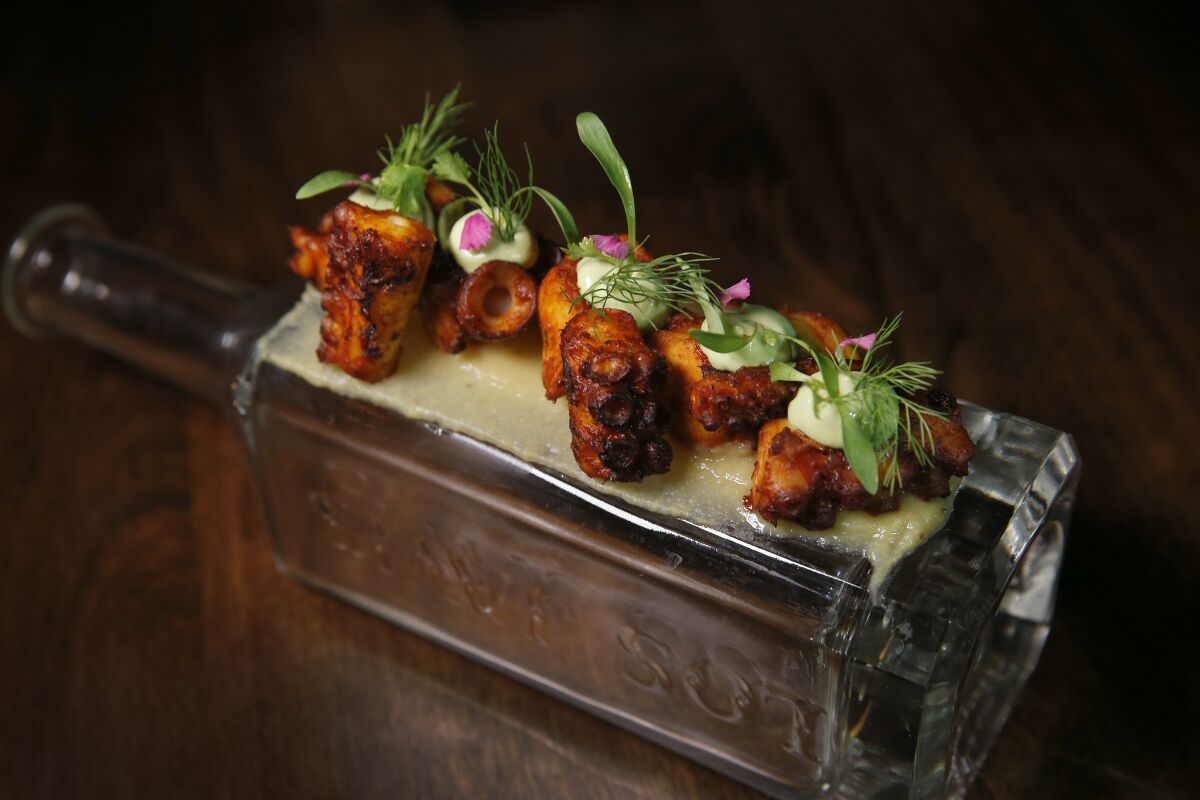 Grilled octopus served atop a mezcal bottle with chorizo salso, sweet plantain and a puree of avocado at Maestro.