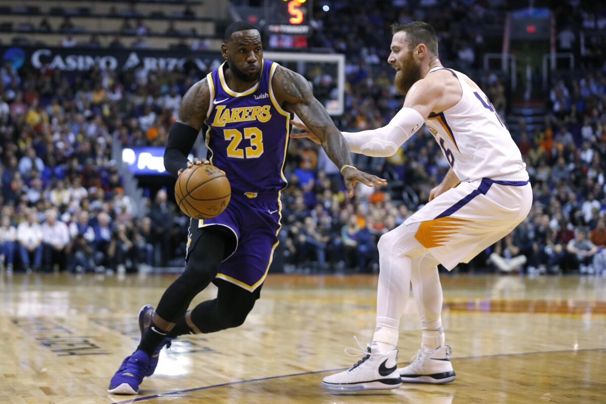 Lakers forward LeBron James drives on Phoenix Suns center Aron Baynes in the first half on Tuesday in Phoenix.
