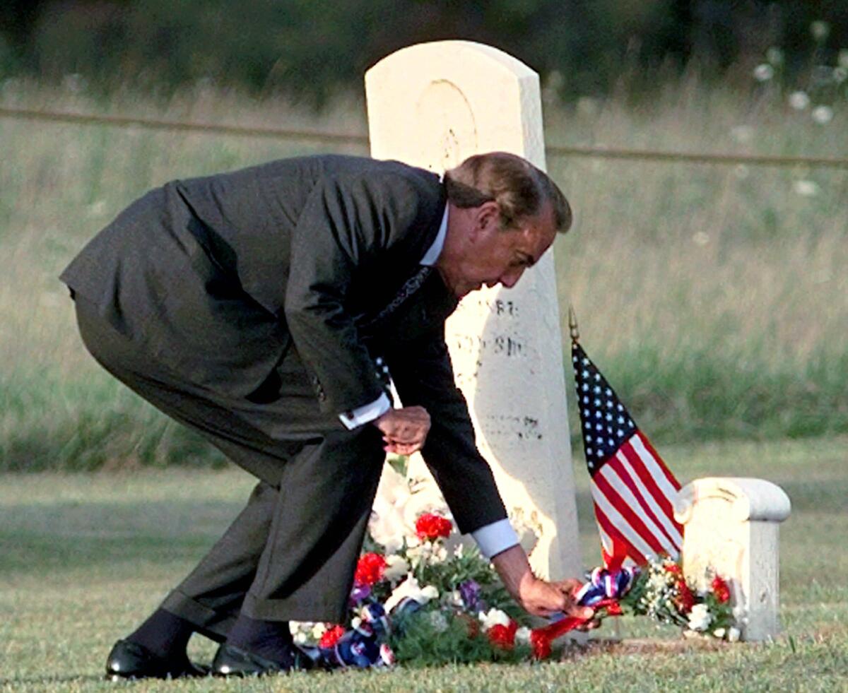 Republican presidential candidate Bob Dole places flowers at the grave of his great, great grandfather, Michael Dole, during a visit to his family's home town of Montpelier, Ohio, Thursday, Sept. 12, 1996. (AP Photo/Eric Draper)
