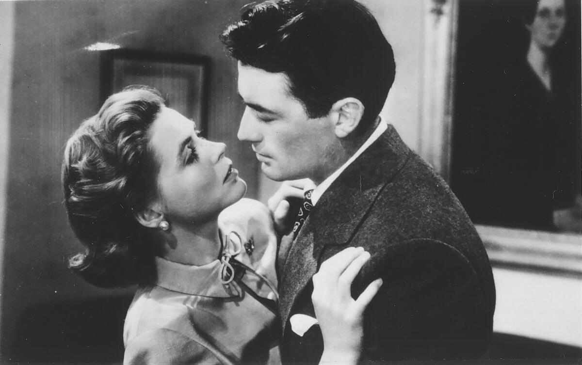 A black-and-white movie still of a man embracing a woman
