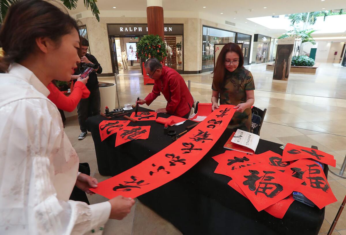 Calligraphers Eve Xu and Wendy Wang make banners of Chinese characters at South Coast Plaza's Lunar New Year celebration.