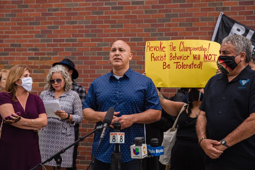 Parents from Orange Glen High spoke at a June rally in front of Coronado High; one carried a sign against racism.