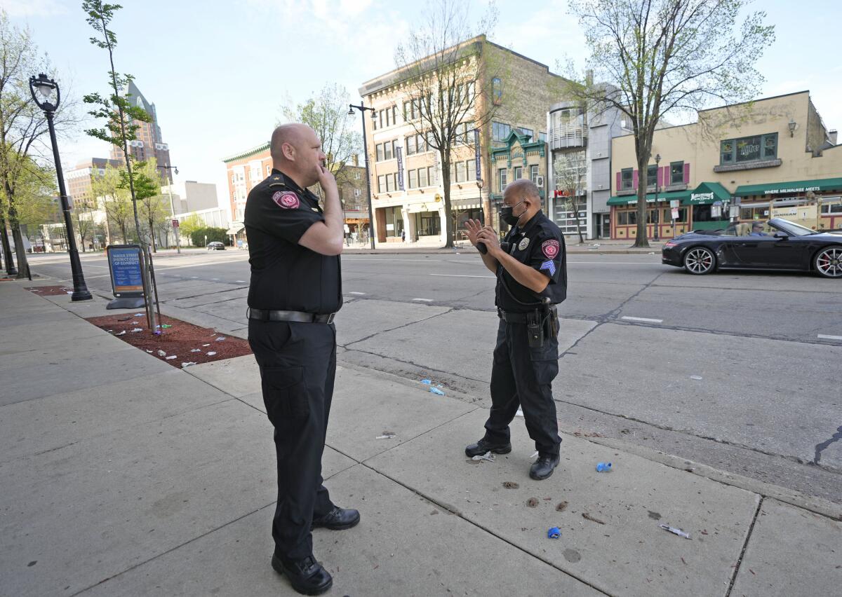 Officers investigate the scene of a shooting on a city street.