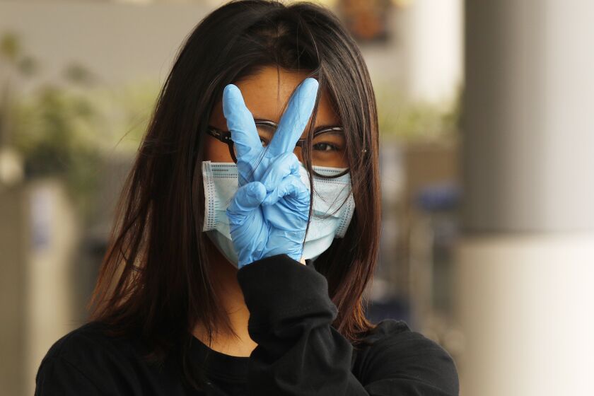LOS ANGELES, CA - MAY 11: Yiran Zou, a student at the California College of Art in San Francisco prepares to fly home to China at Tom Bradley International Terminal, Los Angeles International Airport (LAX) which is now requiring travelers to wear face covering to help keep fellow passengers and crew safe by limiting the spread of the coronavirus Covid-19. The new requirements for wearing face masks in Los Angels began Monday at LAX and on local public transit. LAX on Monday, May 11, 2020 in Los Angeles, CA. (Al Seib / Los Angeles Times)