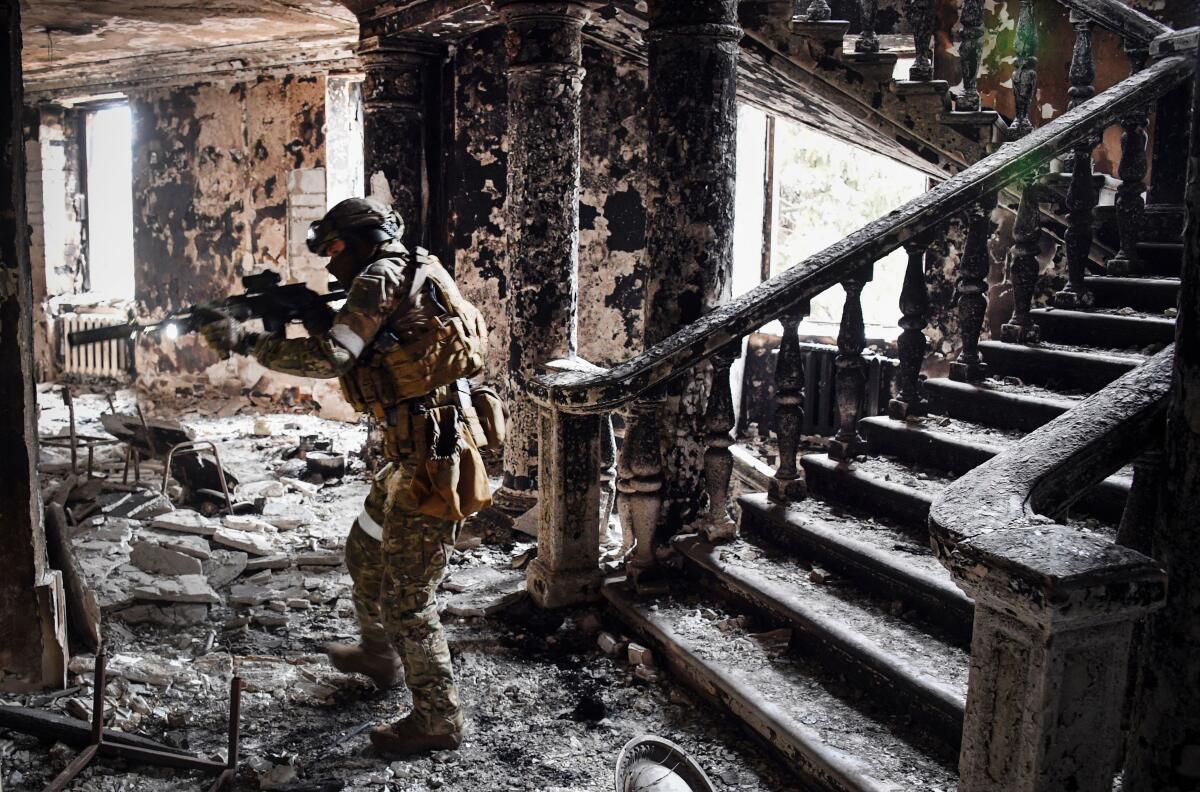 A uniformed person holds up a weapon in a heavily damaged space.