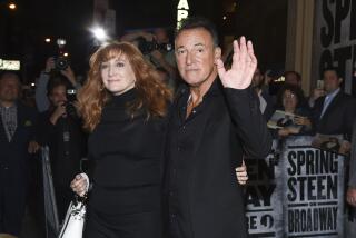 Patti Scialfa and Bruce Springsteen, both dressed in black, hug while greeting fans at opening night of his Broadway show