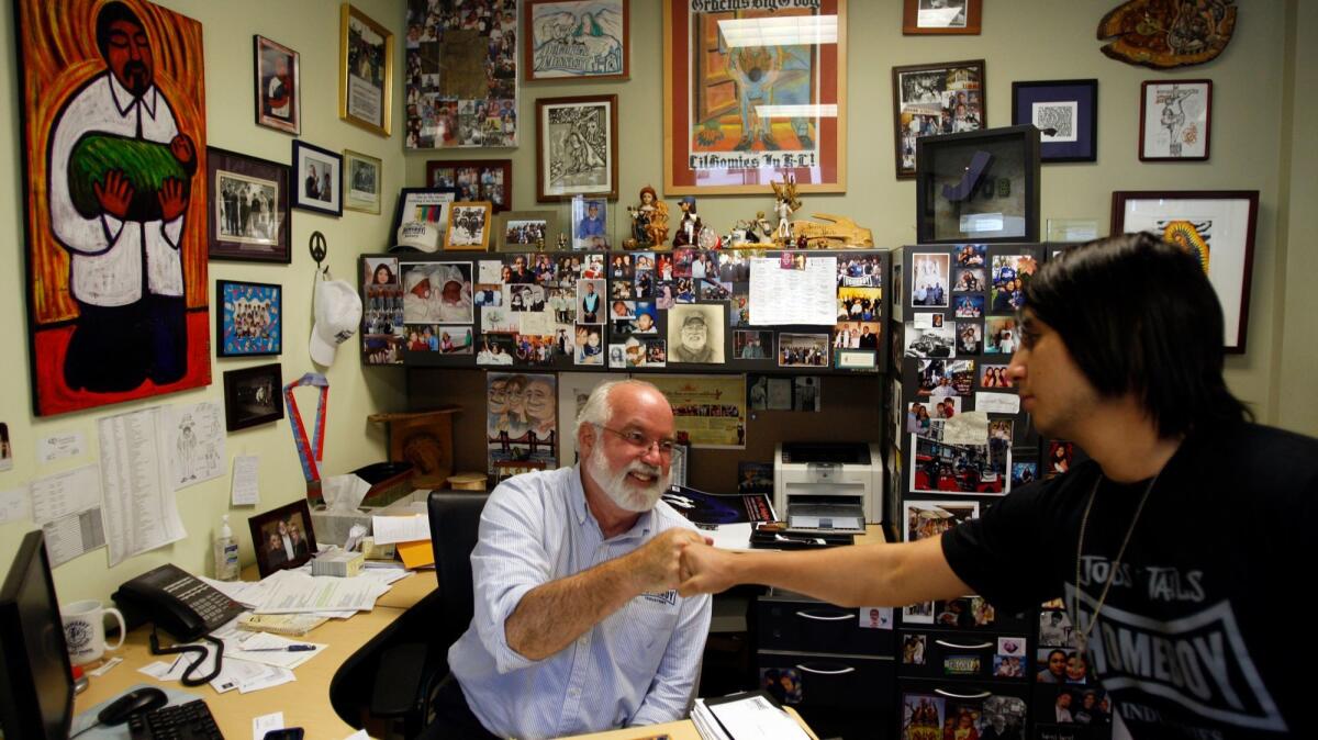 Father Gregory Boyle bumps fists with his assistant Alex Jimenez at Homeboy Industries headquarters in Los Angeles in 2010.