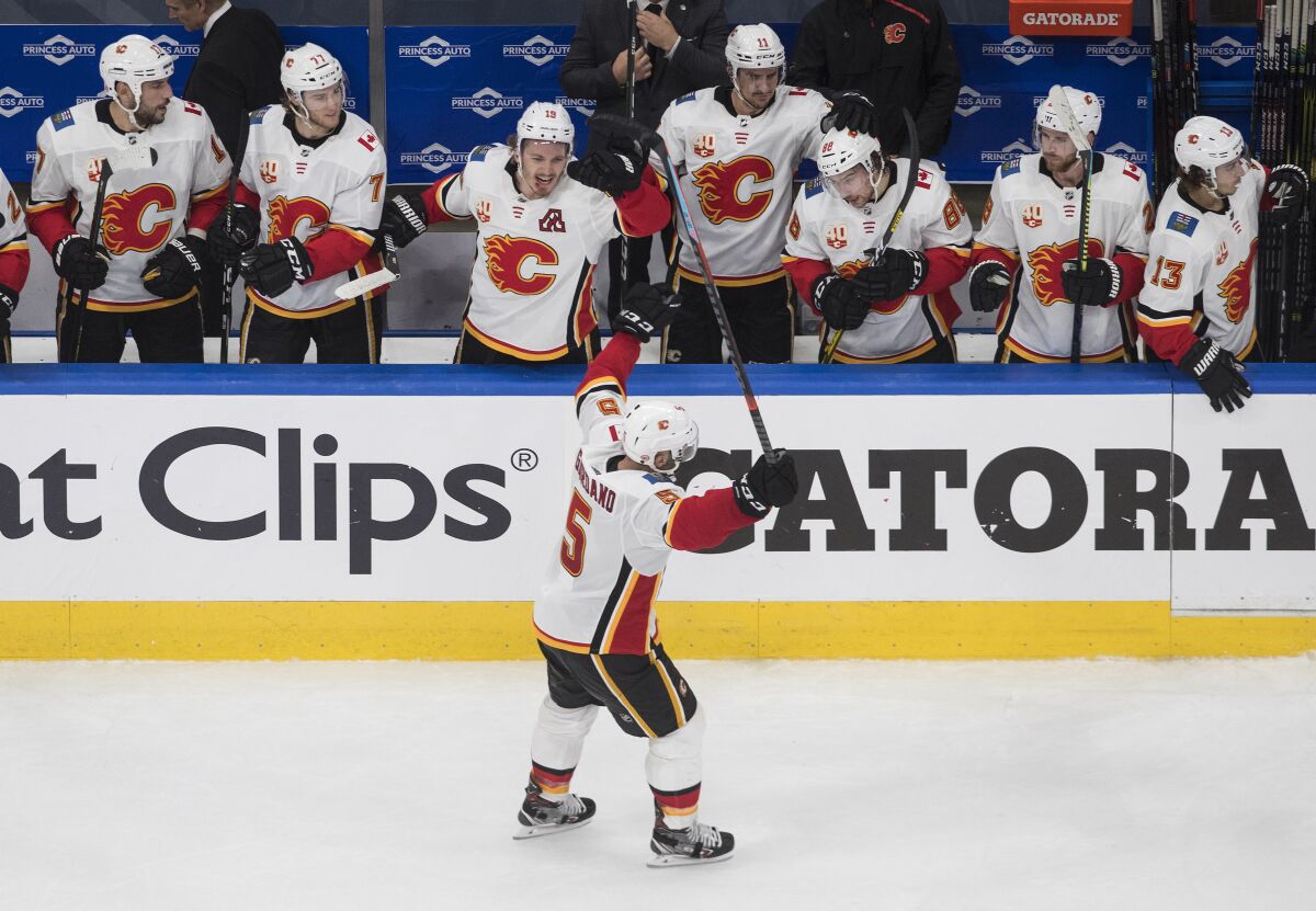 Calgary Flames' Mark Giordano (5) celebrates an empty-net goal with teammates against the Winnipeg Jets during the third period of an NHL qualifying round game, in Edmonton, Alberta, Thursday, Aug. 6, 2020. (Jason Franson=/The Canadian Press via AP)