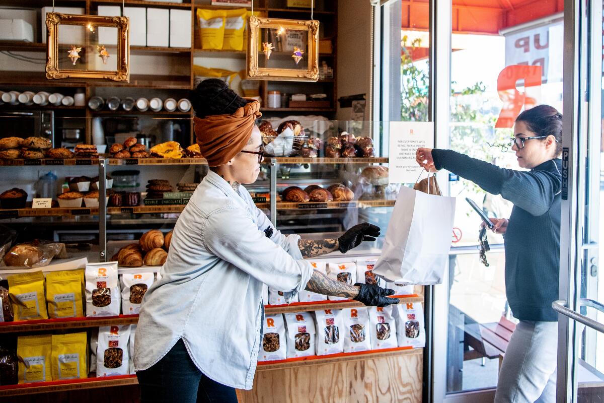 Nicole Medina brings a customer her order at Rõckenwagner Bakery & Cafe on Friday, March 27, 2020.