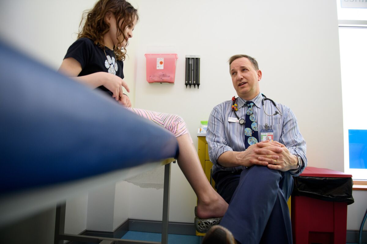 Dr. Todd Wolynn does a routine checkup on Millie Rothstein, 11, at his office in Pittsburgh.