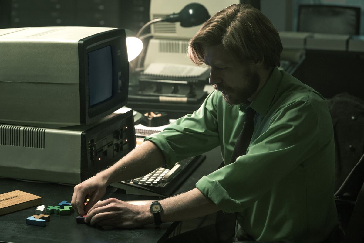 Nikita Efremov sorting pentomino pieces next to a computer in "Tetris."