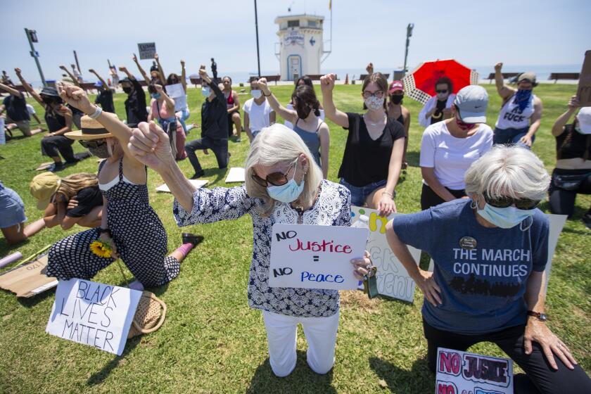 Margo Ganson, left, and Molly Pritchard kneel for 9 minutes during a Black Lives Matter protest at Main Beach in Laguna Beach on Wednesday, June 10.
