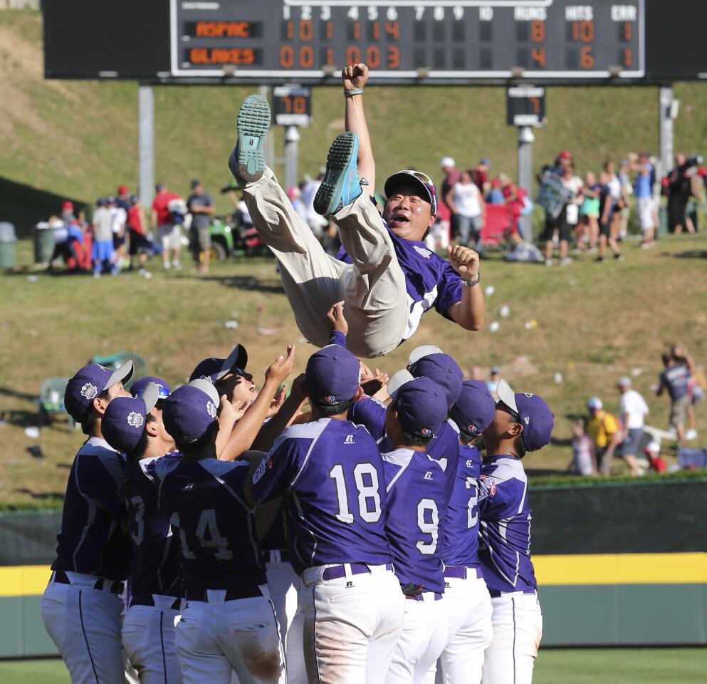 South Korean players celebrate their 8-4 win over Jackie Robinson West by throwing coach Jong Wook Park up in the air.