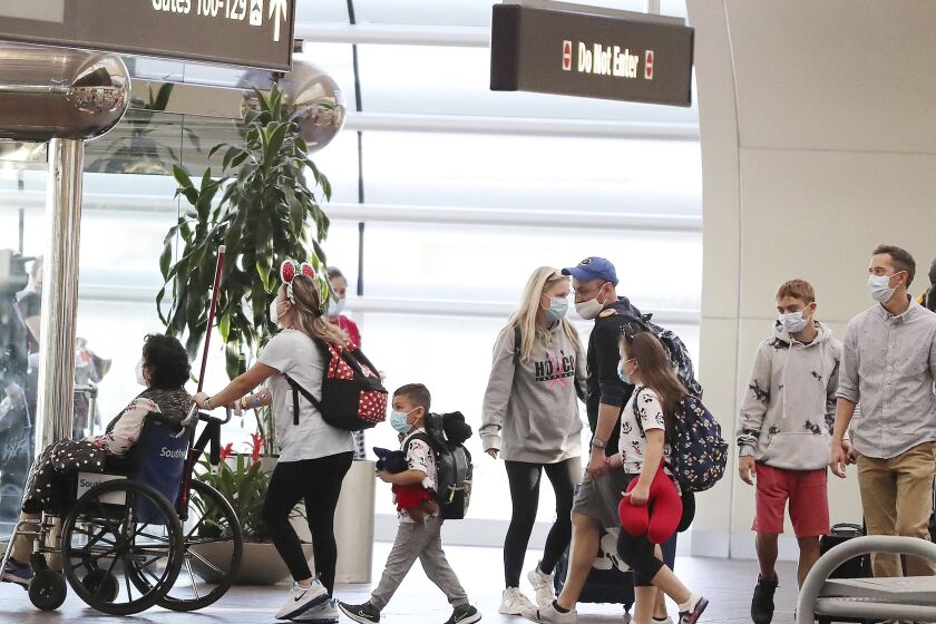 Travelers walk through Terminal A at Orlando International Airport on Christmas Day, Saturday, Dec. 25, 2021. (Stephen M. Dowell/Orlando Sentinel via AP)