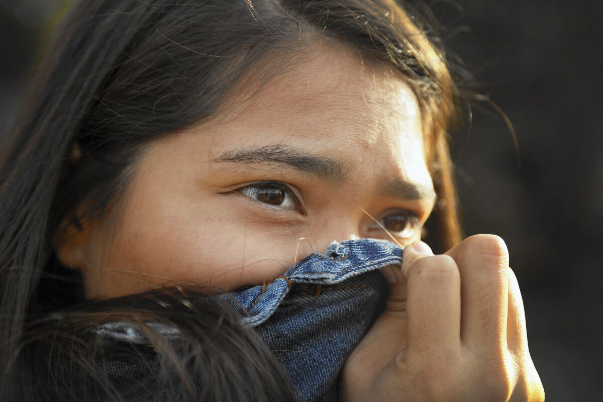 Ashley Hernandez, 23, a youth organizer with Communities for a Better Environment, holds her jacket over her nose as fumes emanate from a residential oil drilling operation in her Wilmington neighborhhod.