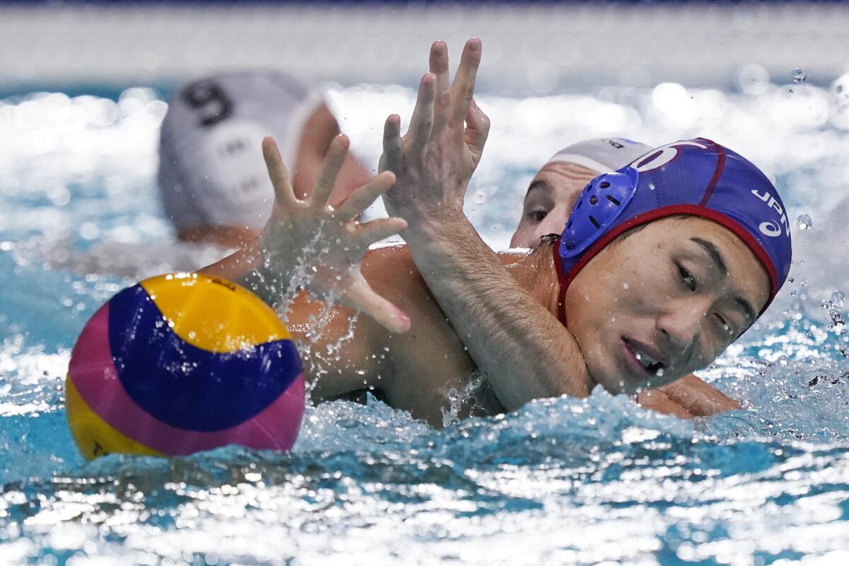 Japan's Toi Suzuki tries to retrieve the ball in the water as he is held by Greece's Konstantinos Genidounias.