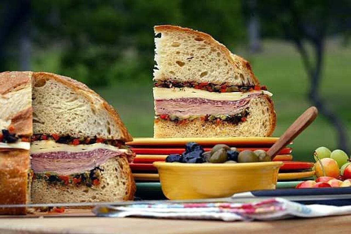 Layer cured meats, provolone and an olive-vegetable relish on a large, round loaf to make a substantial and satisfying muffuletta.