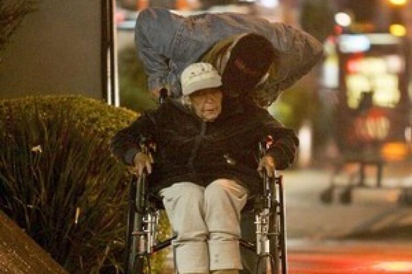 Larry Wilkerson pushes his mother, Bessie Mae Berger, in a wheelchair. They were living in their SUV until October, when a nonprofit stepped in to provide affordable housing.