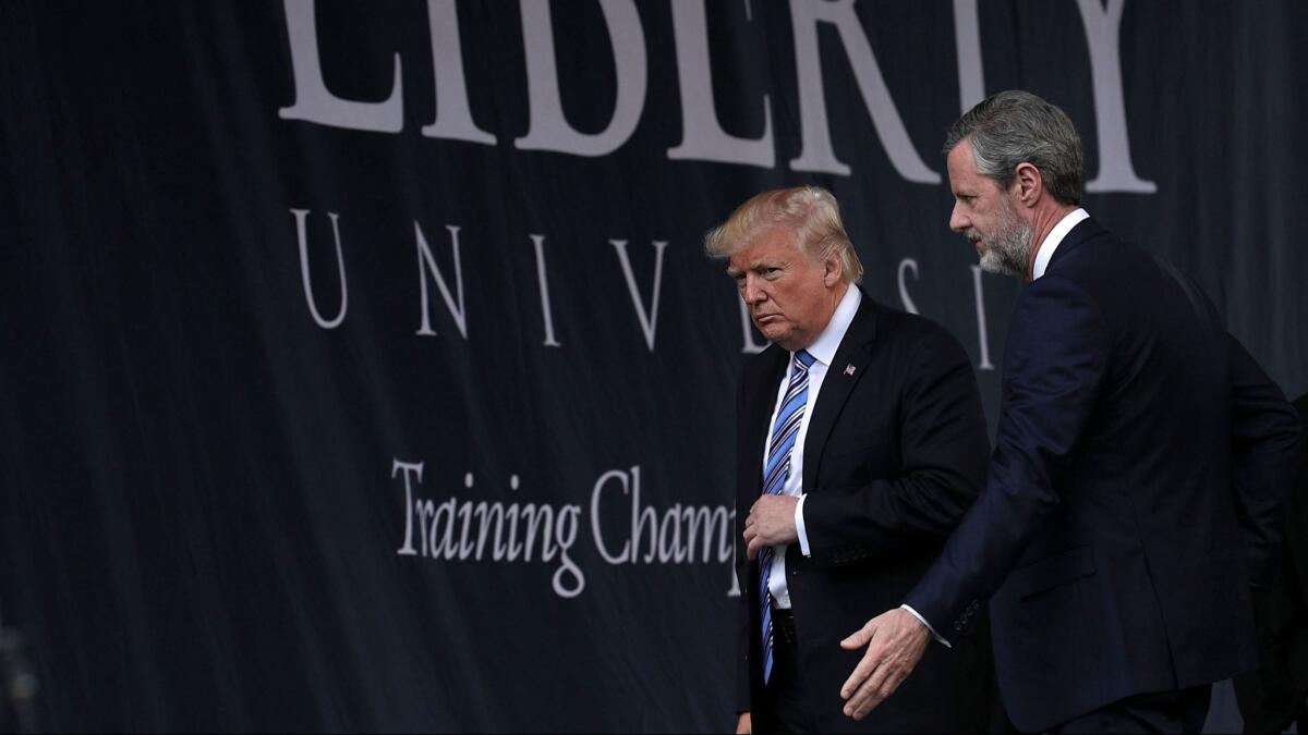 Accompanied by President Jerry Falwell (R), U.S. President Donald Trump (L) leaves after he delivered keynote address during the commencement at Liberty University May 13, 2017 in Lynchburg, Virginia.