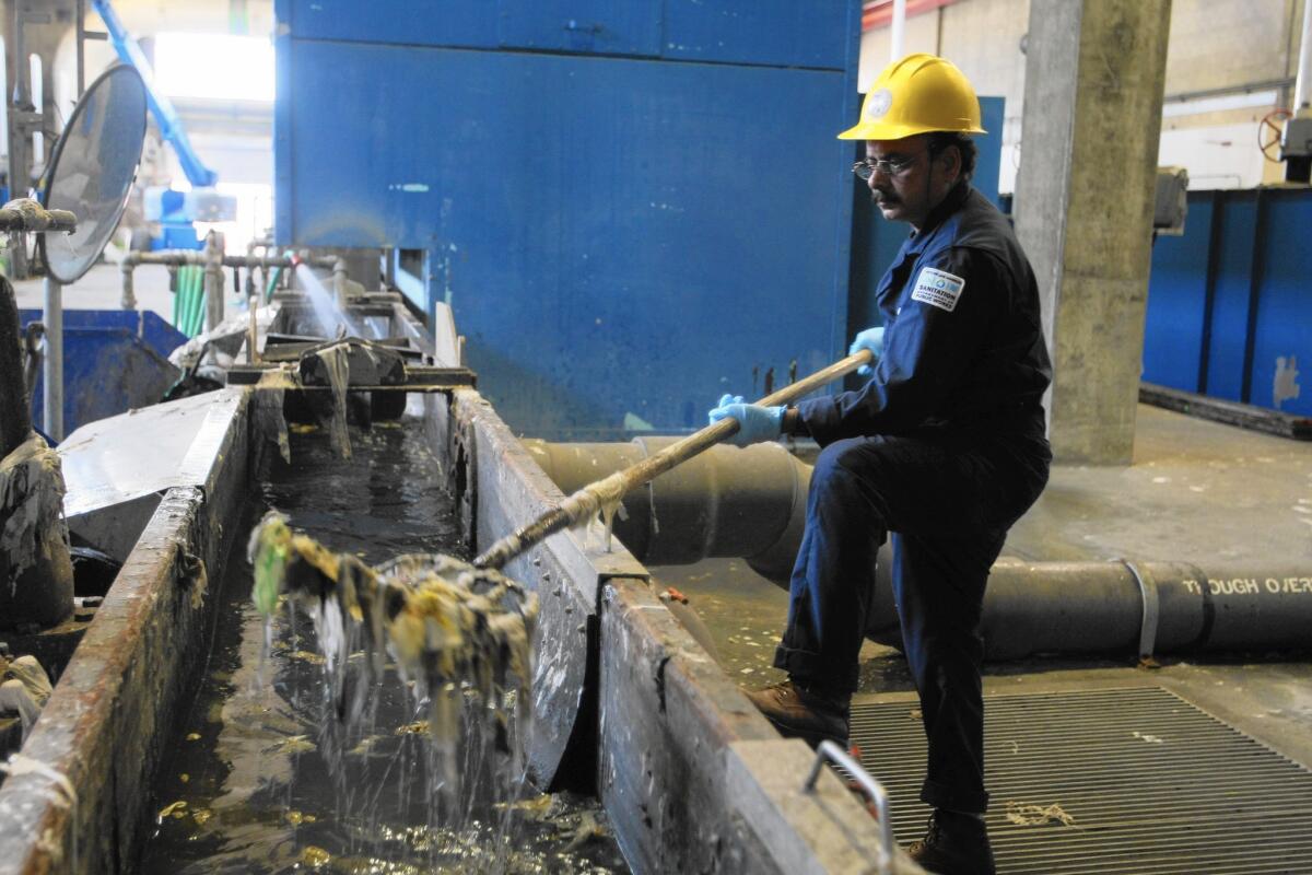 A worker at L.A.'s Hyperion sewage treatment facility removes trash that has been separated from incoming wastewater.