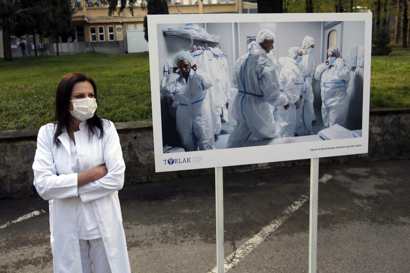 A Torlak Institute's employee waits for the visit of Serbian President Aleksandar Vucic in Belgrade, Serbia, Thursday, April 15, 2021. Serbia has announced it will begin packing and later producing Russia's Sputnik V coronavirus vaccine, which would make it the first European state outside Russia and Belarus to begin manufacturing the jab. (AP Photo/Darko Vojinovic)