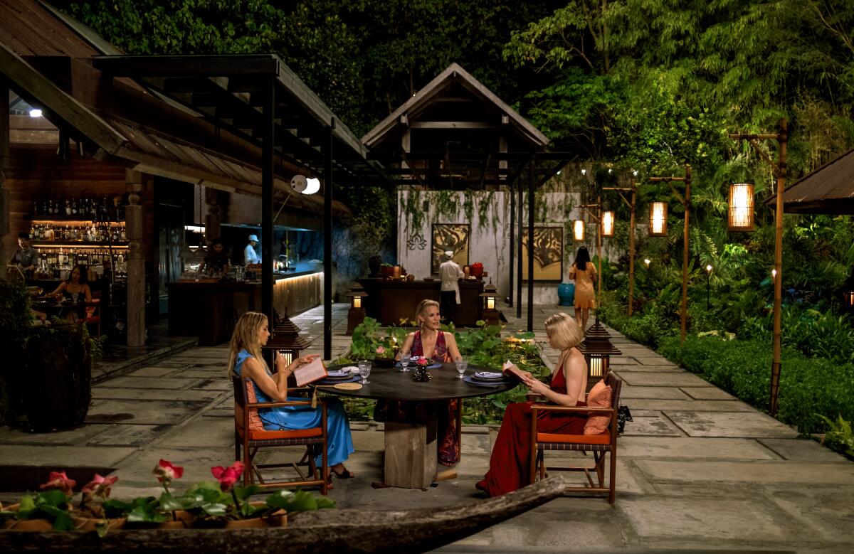 Three women seated astatine a meal table.