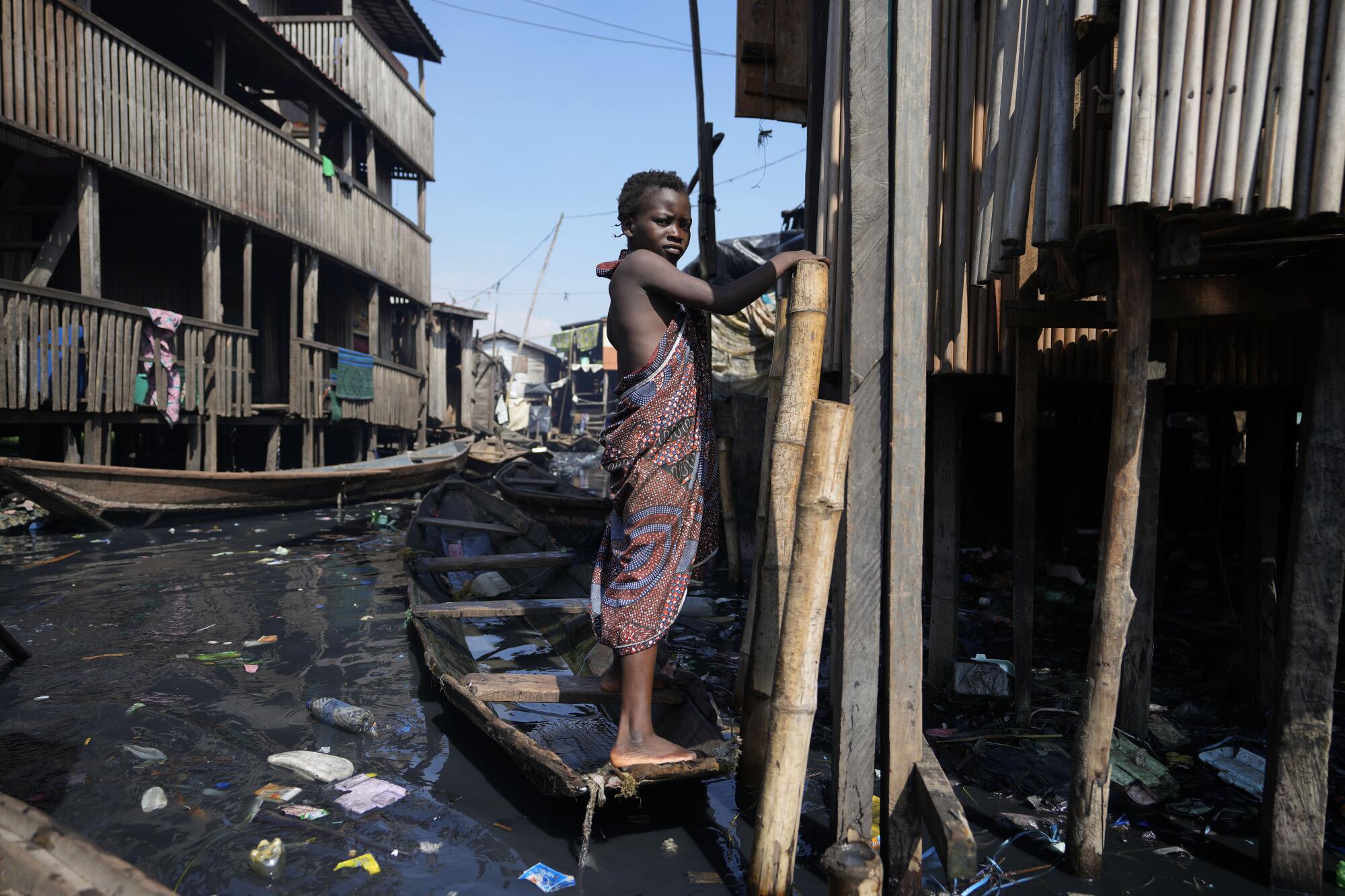 Ein Kind steht in einem Slum in Lagos, Nigeria, umgeben von Müll in schmutzigem Wasser.