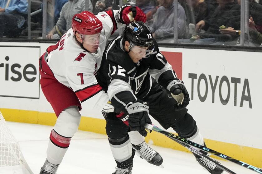 Los Angeles Kings center Trevor Moore, right, moves the puck as Carolina Hurricanes.
