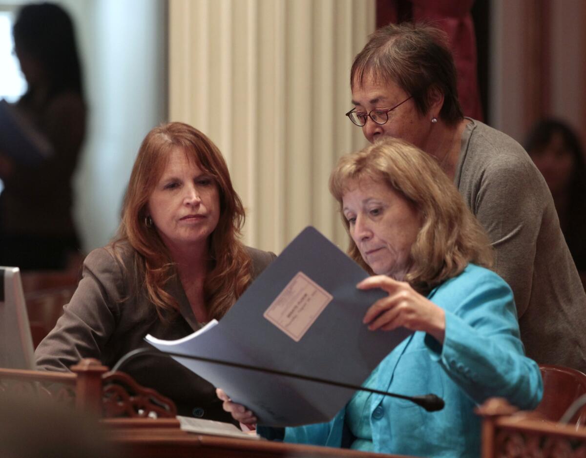 Democratic state Sens. Noreen Evans of Santa Rosa, left, Ellen Corbett of San Leandro, right, and Carol Liu of Pasadena, standing, look over papers at the Capitol in Sacramento.