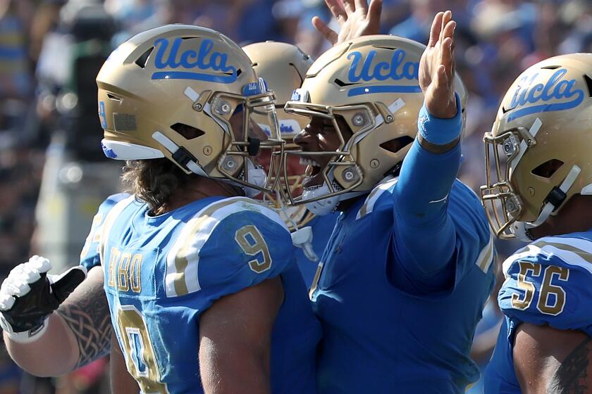 UCLA's Dorian Thompson-Robinson, middle right, and Jake Bobo (9) are fired up after Bobo scored a touchdown Oct. 8, 2022