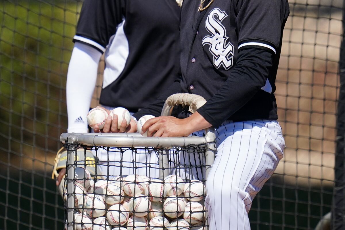 Chicago White Sox minor league players put baseballs back in the basket during batting practice at a minor league spring training workout Thursday, March 10, 2022, in Phoenix. Major League Baseball’s acrimonious lockout ended Thursday when a divided players’ association voted to accept management’s offer to salvage a 162-game season that will start April 7. (AP Photo/Ross D. Franklin)
