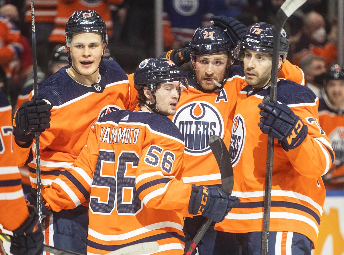 Edmonton Oilers' Jesse Puljujarvi (13), Kailer Yamamoto (56), Leon Draisaitl (29) and Evan Bouchard (75) celebrate a goal against the Calgary Flames during the second period of an NHL hockey game Saturday, Jan. 22, 2022, in Edmonton, Alberta. (Jason Franson/The Canadian Press via AP)