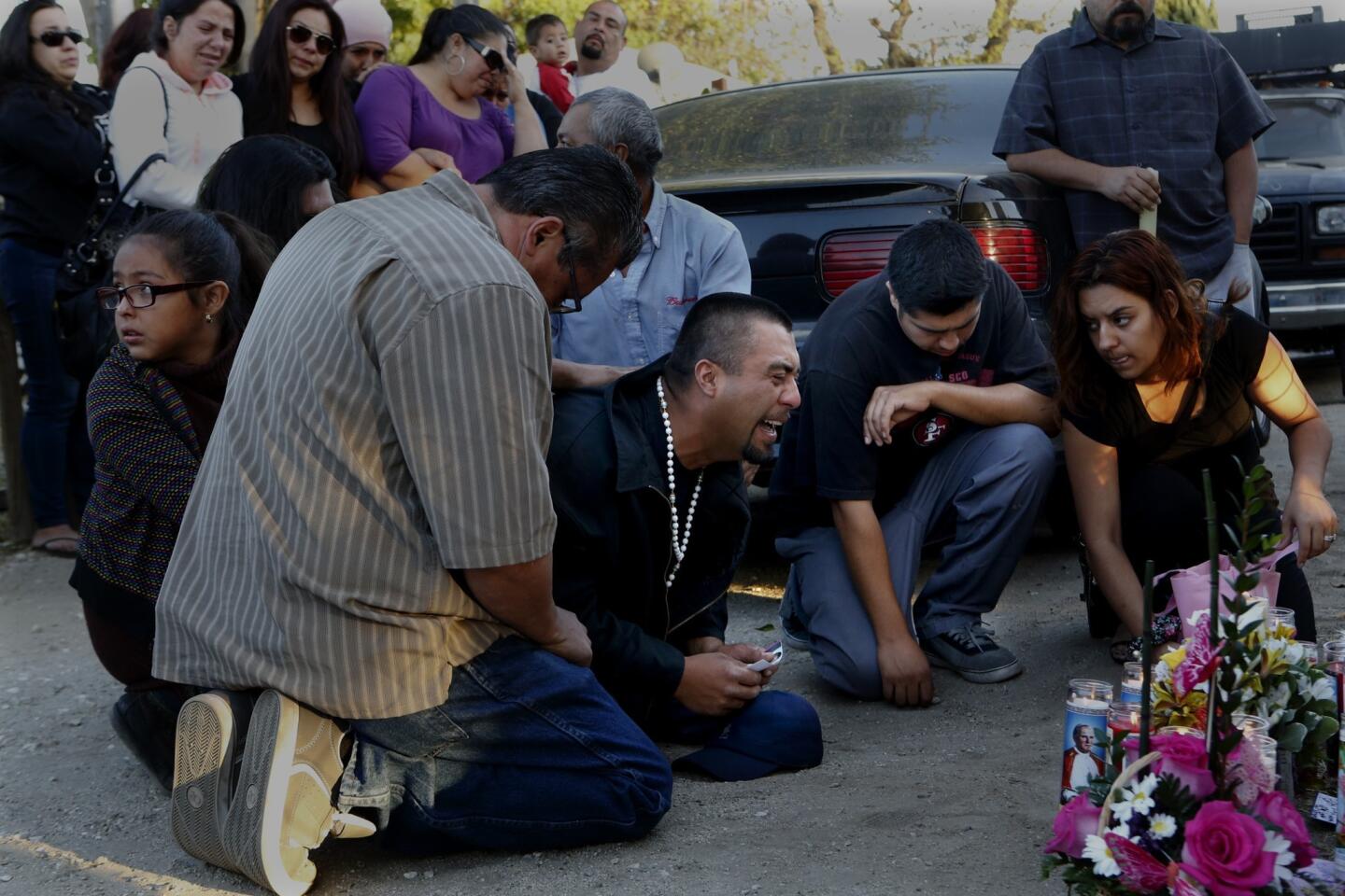 Rudy Coronado, center, the father of the slain girls, is comforted during a vigil.