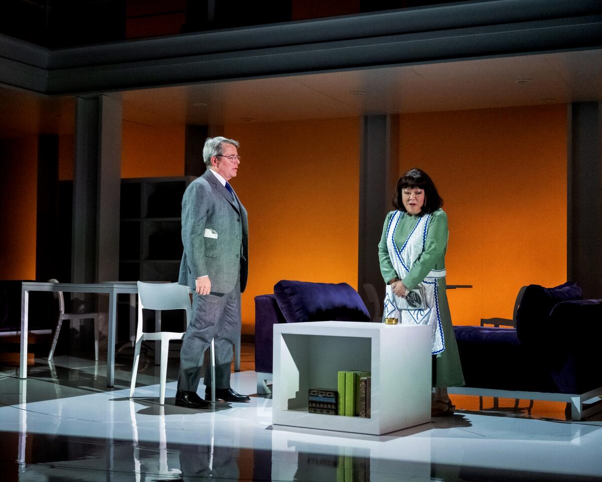 Actors portraying husband and wife onstage in a spare kitchen set