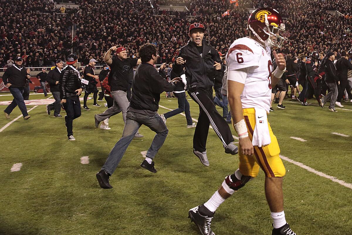 Utah fans storm the field as USC quarterback Cody Kessler walks off in defeat after the Trojans' loss in 2014.