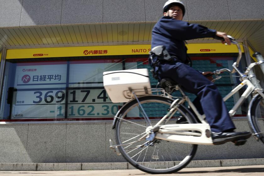 A police officer rides a bicycle past an electronic stock board showing Japan's Nikkei 225 index at a securities firm Friday, April 19, 2024, in Tokyo. Asian markets tumbled Friday, with Japan's benchmark Nikkei 225 down more than 3% on heavy selling of semiconductor-related shares.(AP Photo/Eugene Hoshiko)