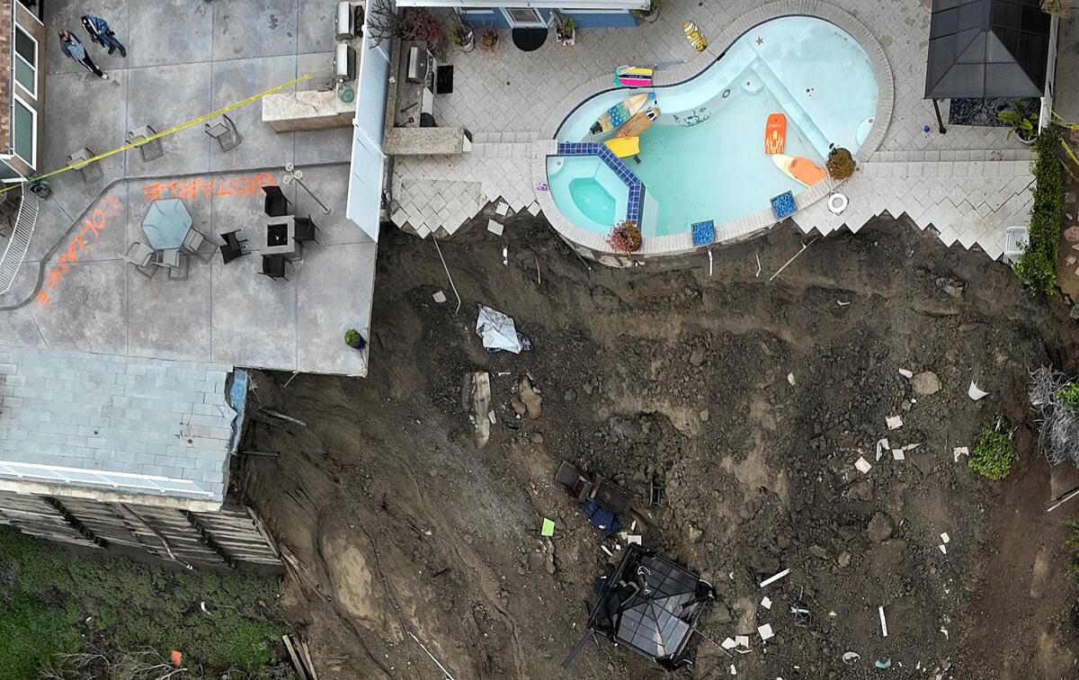 People view what's left of their back yard and pool where four cliff-side, ocean-view apartment buildings were evacuated.