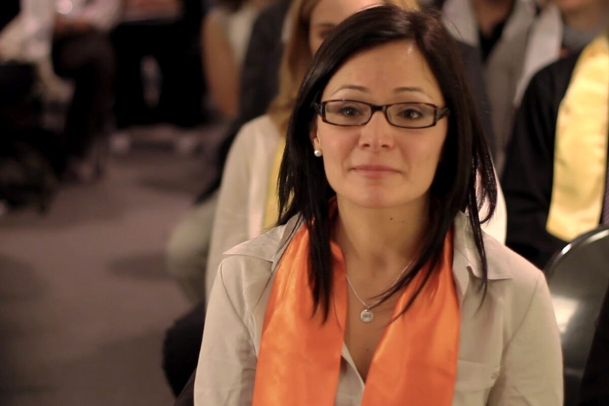 A seated woman wears glasses and an orange scarf.