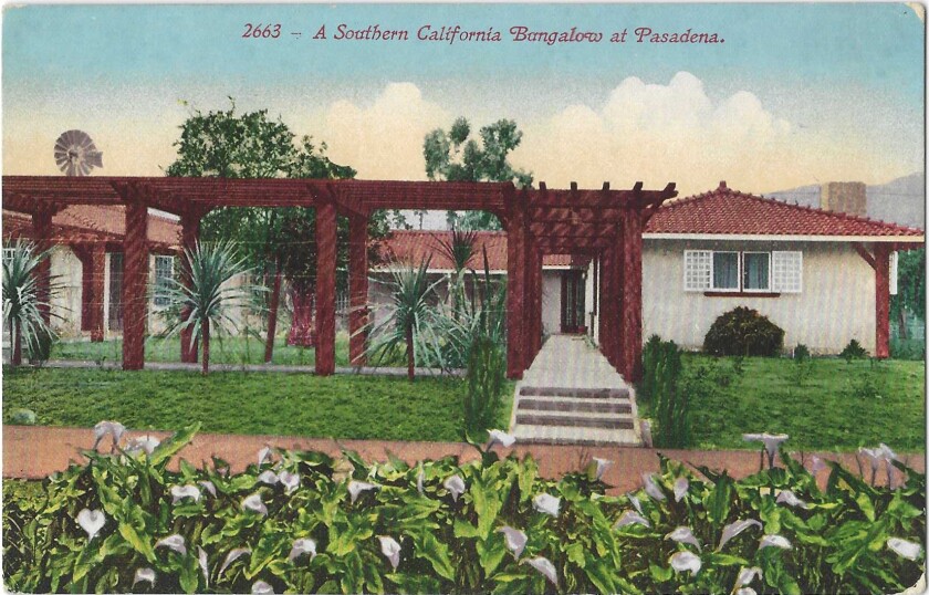 Lillies bloom in the foreground of a tile-roofed bungalow with a long walkway and portico leading to the home