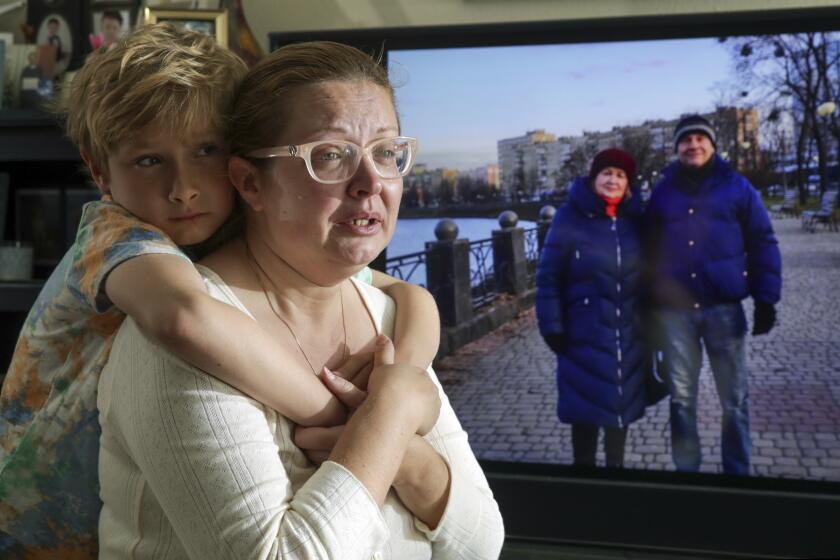 Huntington Beach, CA - March 05: Ganna Hovey 37, occasionally Facetimes with her parents, Oleksandr Usenko, 65, and her mother Svitlana Usenko, 57, who have taken refuge in the basement of their apartment complex in Kharkiv since the start of the Russian invasion. Ganna Hovey who is distraught over her parents situation, is comforted by her 7-year-old son Leonardo Hovey at apartment on Saturday, March 5, 2022 in Huntington Beach, CA. (Irfan Khan / Los Angeles Times)