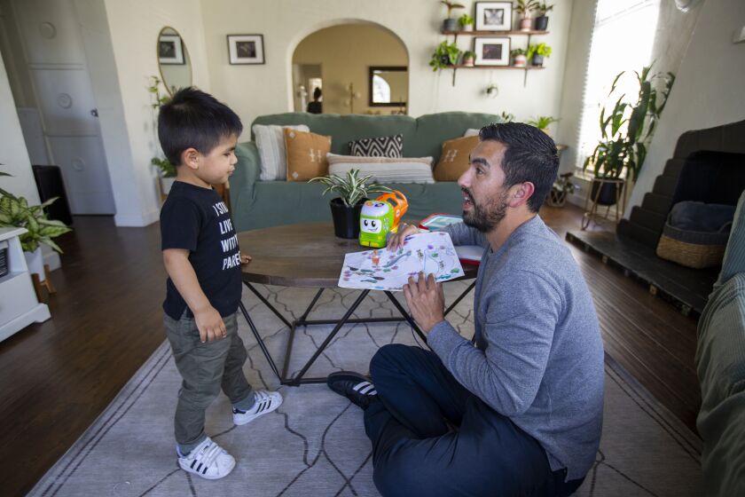 MAYWOOD, CA - March 31: Eric Eztli, shown playing with his two-year-old son, Elias Contreras-Barajas, is a poet and high school teacher who grew up in Bell/South Gate, is the co-founder of Bloom Homie, an Instagram page geared at "detoxifying masculinity" by engaging users in conversations that range from violence against women to homophobia to mental health. The account is part of a wider effort that includes weekly meetings with men across L.A. county, as well as a podcast. Photo taken at his Maywood home Wednesday, March 31, 2021. (Allen J. Schaben / Los Angeles Times)