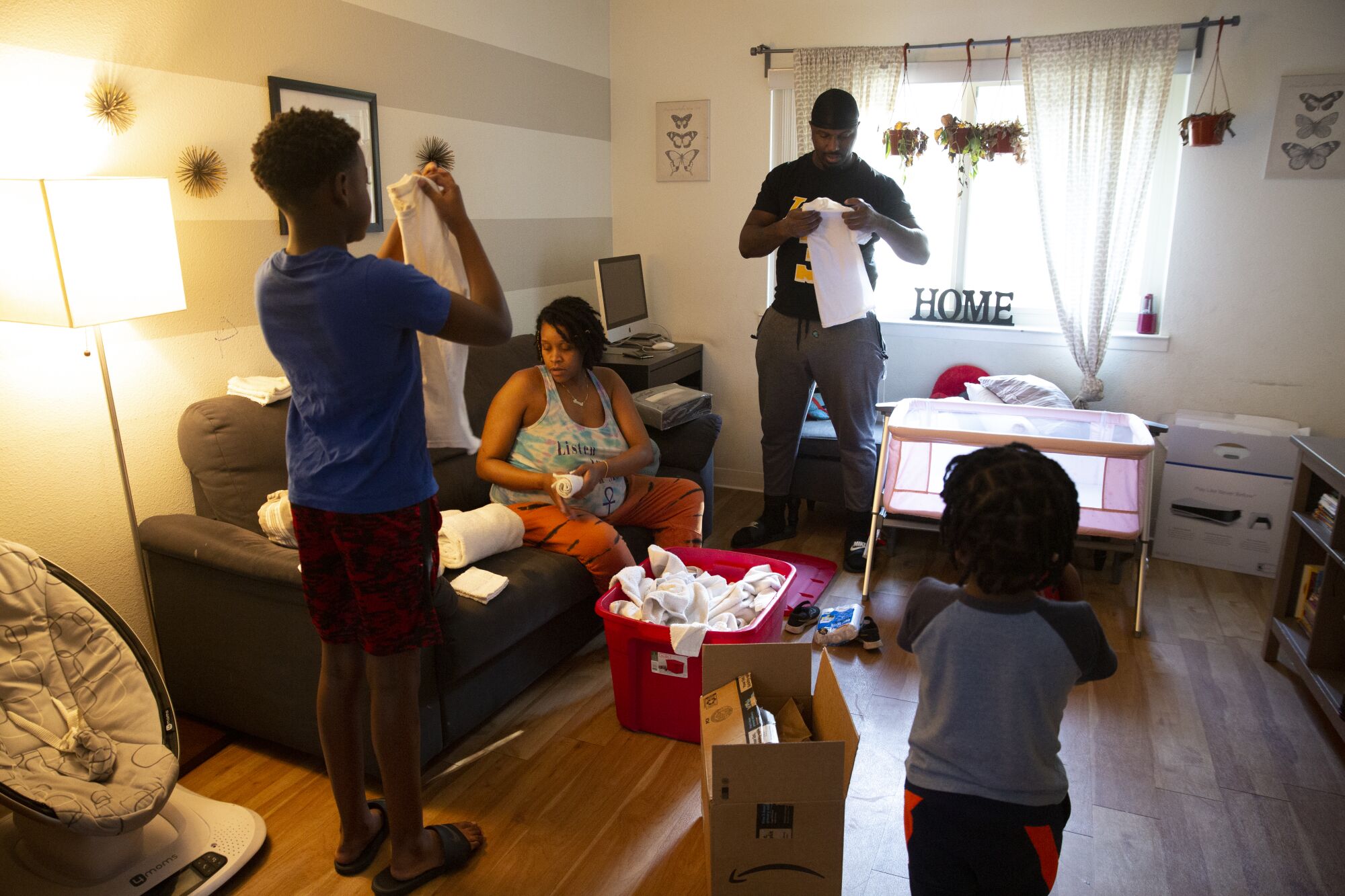 A couple and their children fold laundry in a room