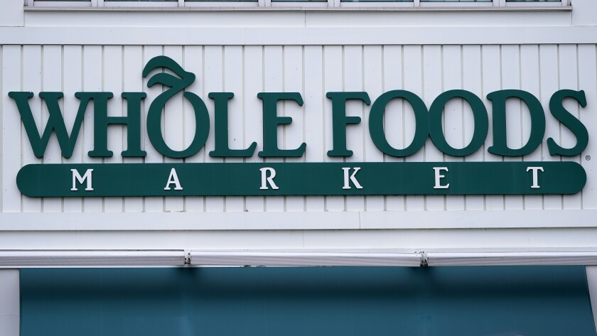 The Whole Foods Market logo is shown on the front of a store, Wednesday, July 14, 2021, in Cambridge, Mass. Amazon, which owns the grocery chain, said Wednesday, Sept. 8, that it will bring its cashier-less technology to two Whole Foods stores for the first time, letting shoppers grab what they need and leave without having to open their wallets. (AP Photo/Charles Krupa)