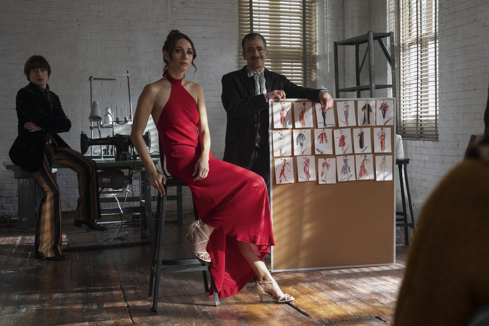 A woman shows off a crimson halter dress by Halston in a scene from "Halston."